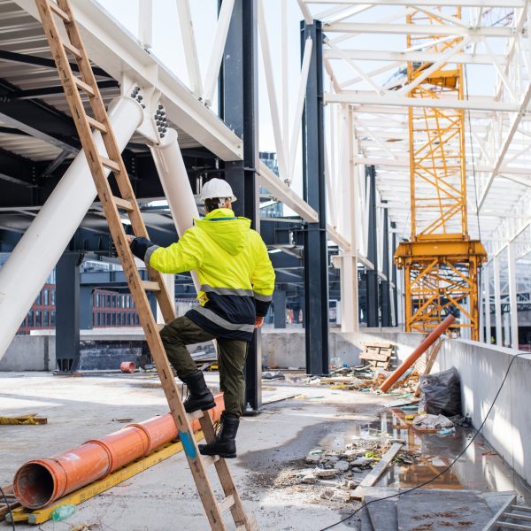 A rear view of man worker outdoors on construction site, working.